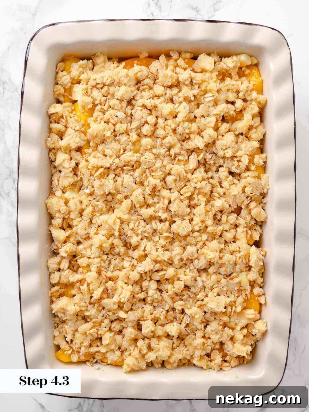 Warm Buttery Peach Crisp 11 Peach crisp ready to bake, with a uniform crumbly topping covering the peach mixture.