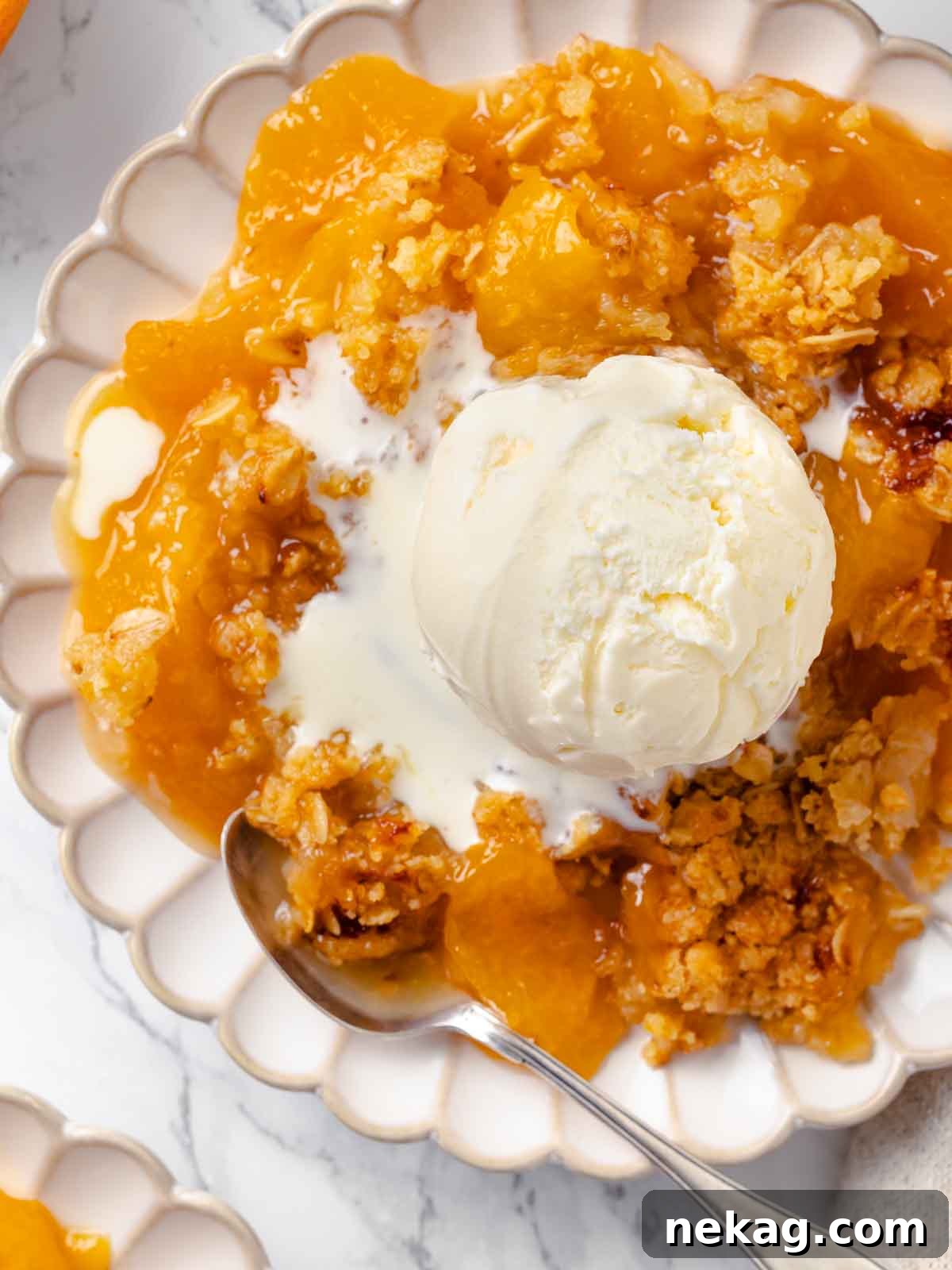 Warm Buttery Peach Crisp 3 Close-up of peach crisp topped with melting vanilla ice cream, showing the creamy texture blending with the crisp.