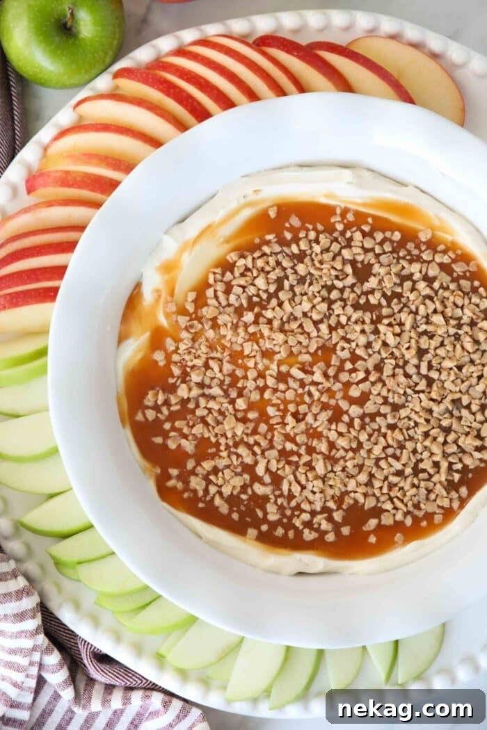 Close-up aerial view of the creamy cream cheese, glossy caramel, and crunchy toffee bits creating an inviting swirl in a white serving bowl.