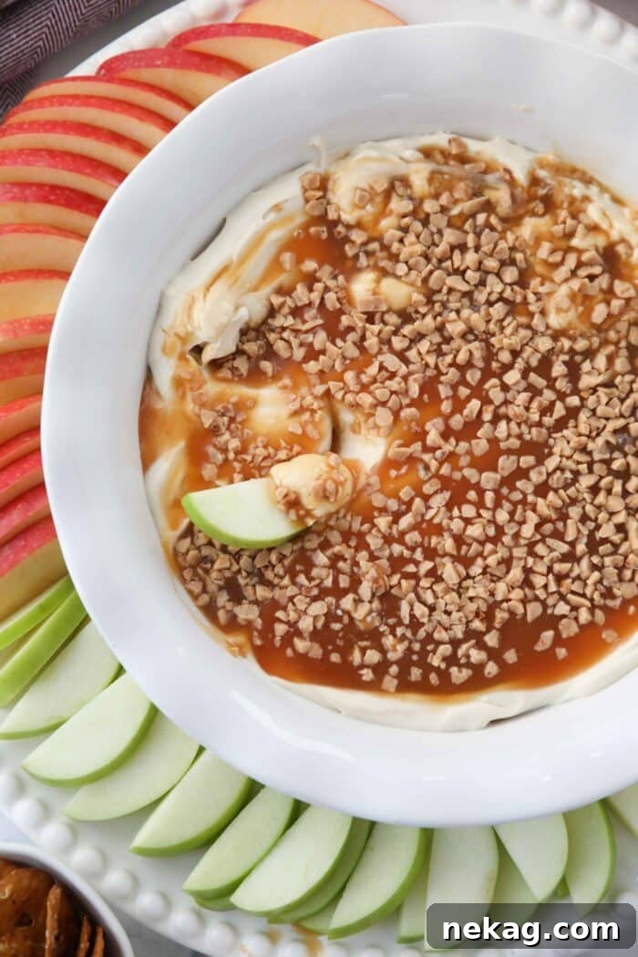 A close-up shot of a single apple slice nestled into the creamy caramel apple dip, capturing the rich texture and delicious toppings.