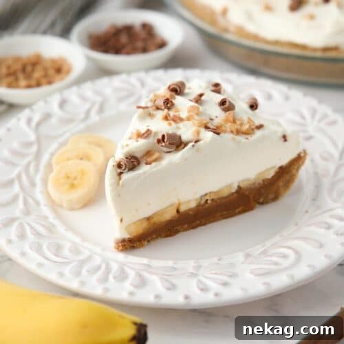 Effortless Banoffee Bliss 12 Side view of banoffee pie showing layers of graham cracker crust, dulce de leche, banana slices, whipped cream and toppings.
