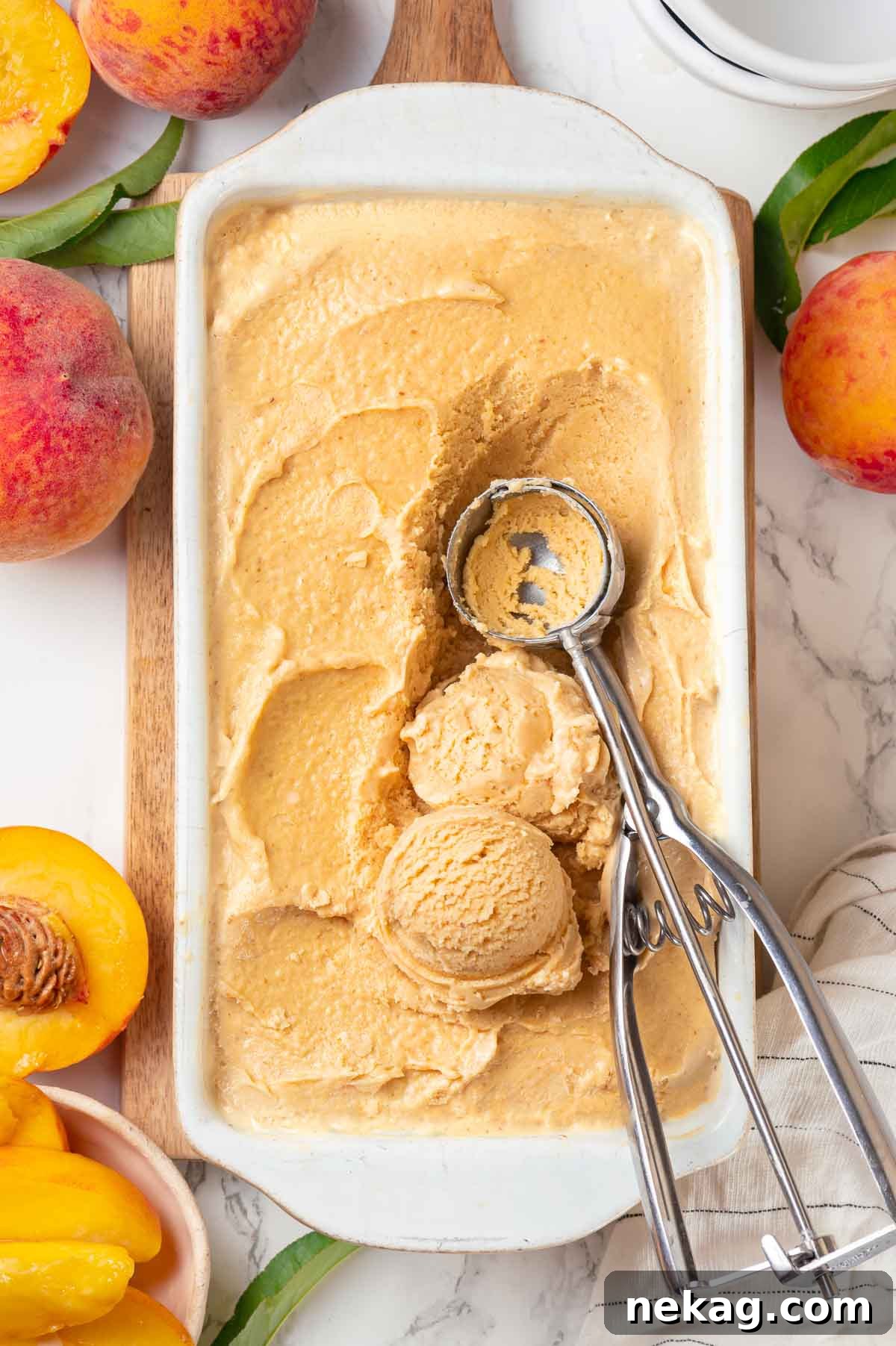 Fresh Peach Bliss 5 Smooth, churned fresh peach ice cream in a white loaf pan, featuring a vintage ice cream scoop for serving.