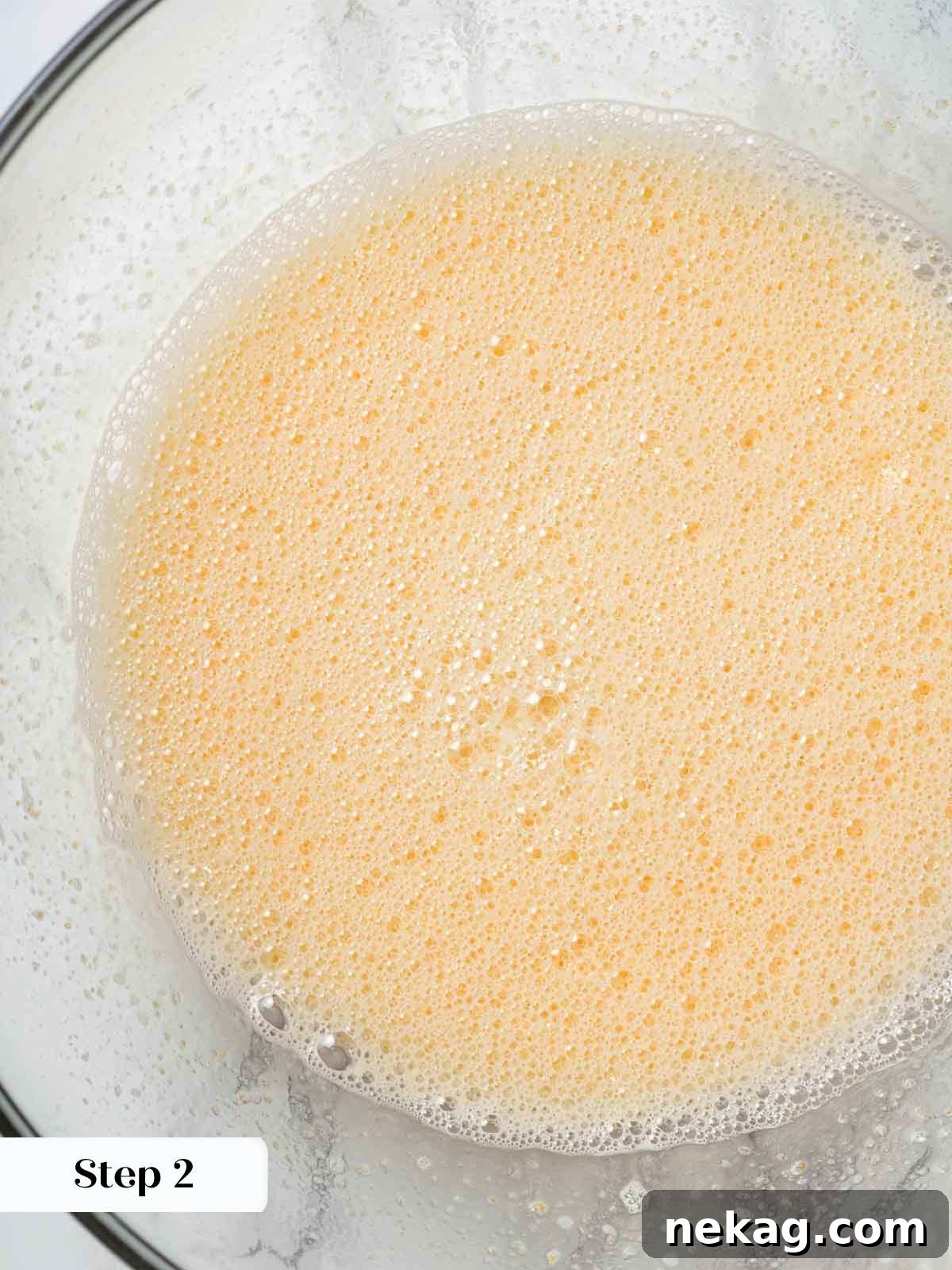 Fresh Peach Bliss 6 Close-up of whisked eggs and granulated sugar in a mixing bowl, forming the creamy base for the ice cream.