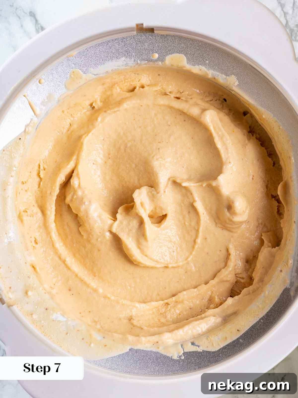 Fresh Peach Bliss 9 Creamy peach ice cream actively churning in an ice cream maker, showcasing its smooth, soft-serve consistency.