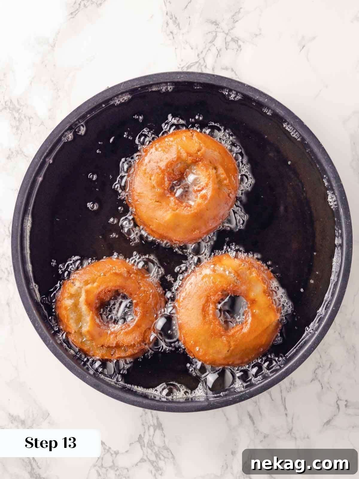 Harvest Apple Cider Donuts 19 Apple cider donuts frying in hot oil, achieving a golden brown color.