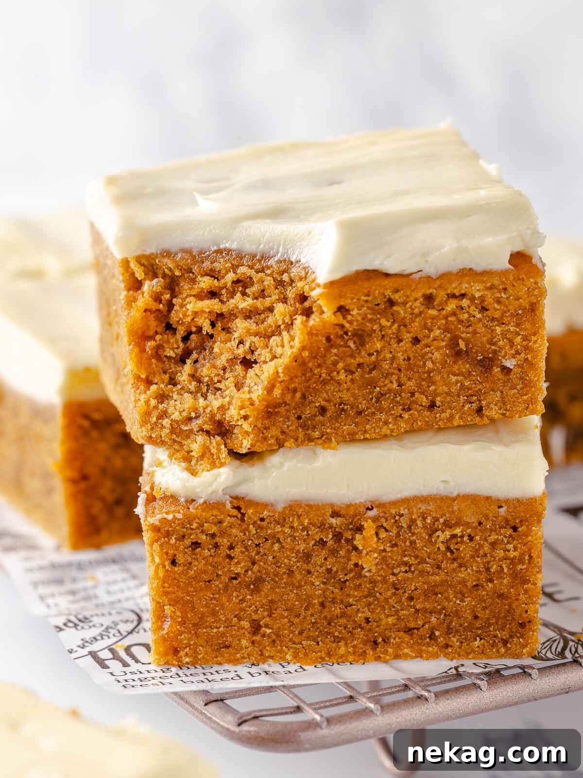 Autumn Spice Squares 2 A perfectly bitten pumpkin bar showcasing its moist, tender interior and creamy frosting.