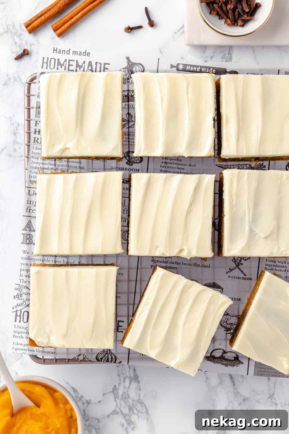 Autumn Spice Squares 17 Beautifully arranged pumpkin bars with frosting on a pristine white marble counter, ready to be enjoyed.