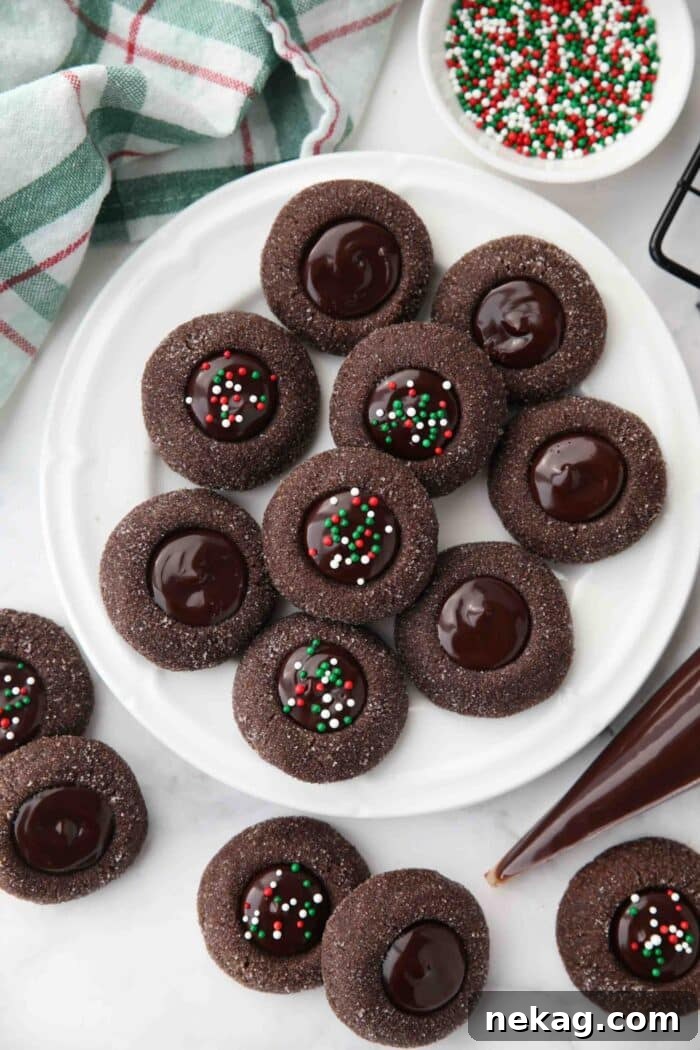 Plate of chocolate thumbprint cookies with ganache centers. Some with holiday sprinkles.