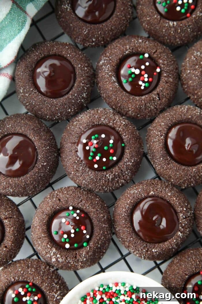 Close up of thumbprint chocolate cookies with ganache centers topped with holiday nonpareils.