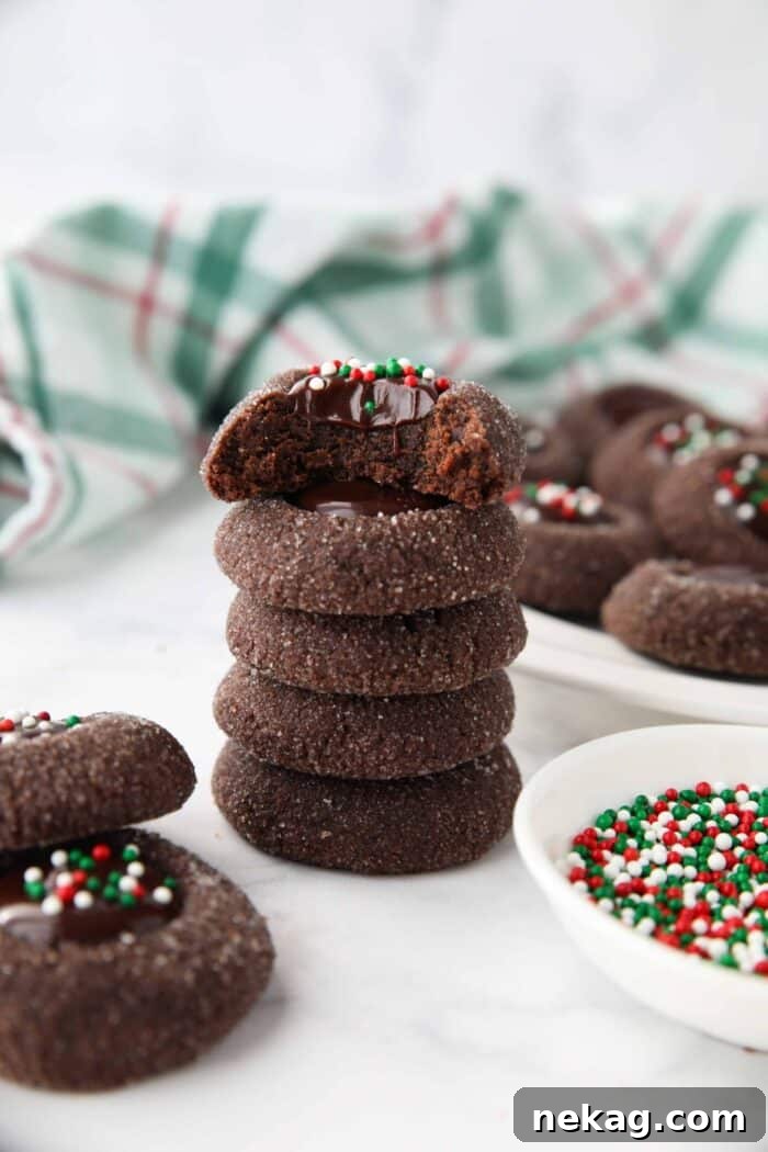 Stack of chocolate thumbprints with a bite taken out of the top one showing ganache center.