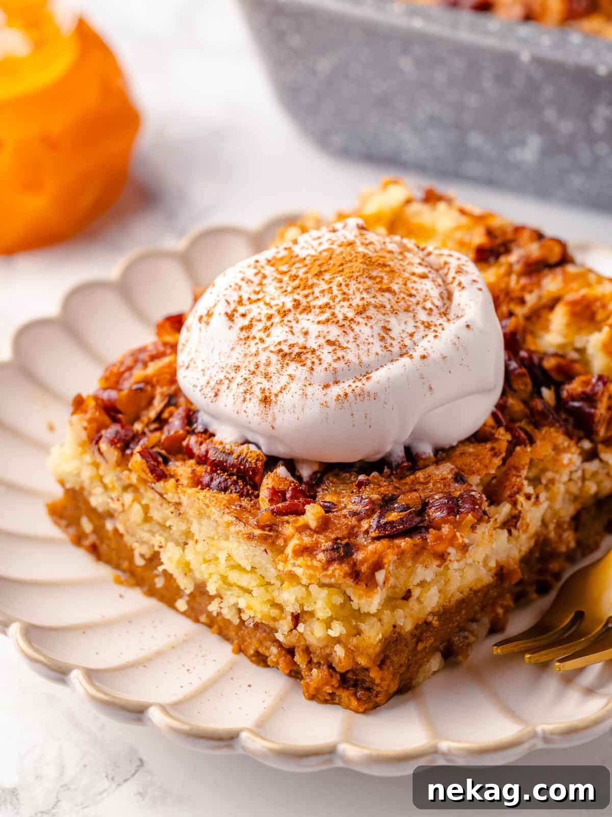 A perfectly sliced piece of golden-brown pumpkin dump cake, revealing distinct layers of creamy pumpkin and crumbly topping, served neatly on a pristine white plate.