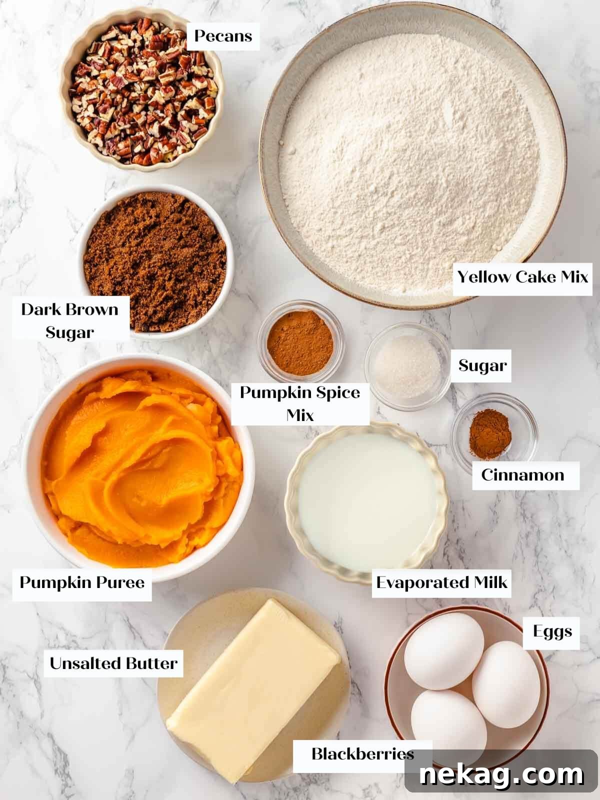 Various essential ingredients for pumpkin dump cake, including cans of pumpkin, evaporated milk, dark brown sugar, eggs, pumpkin spice, a box of yellow cake mix, pecans, cinnamon, and butter, neatly arranged on a pristine white marble countertop, ready for the baking process.