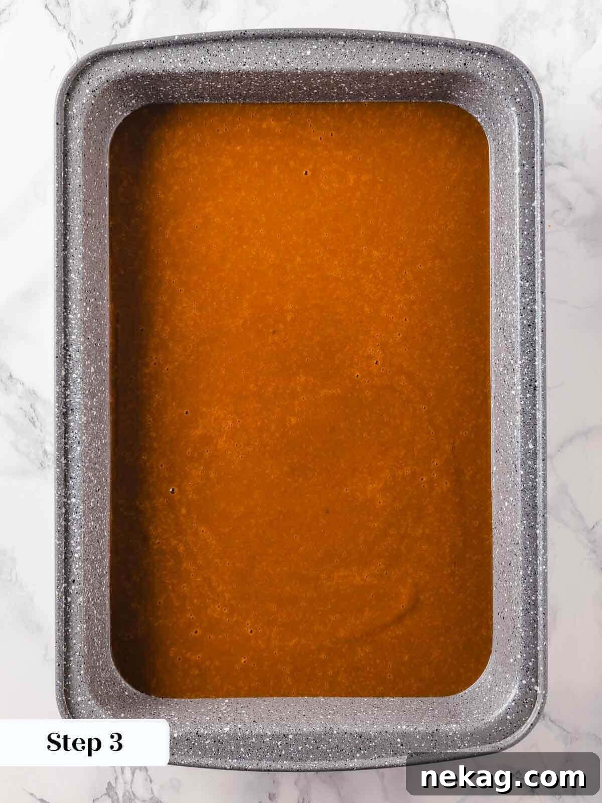 The smoothly whisked pumpkin dump cake mixture poured into the prepared 9x13 inch baking dish, forming a vibrant, even layer across the bottom before any dry toppings are added.