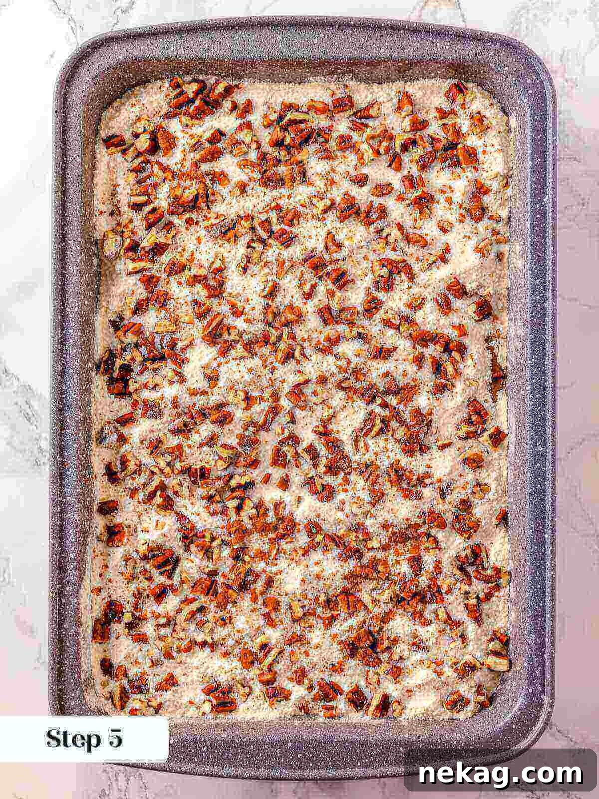 Finely chopped pecans generously sprinkled over the dry cake mix layer on top of the pumpkin dump cake mixture, preparing for the final butter layer.