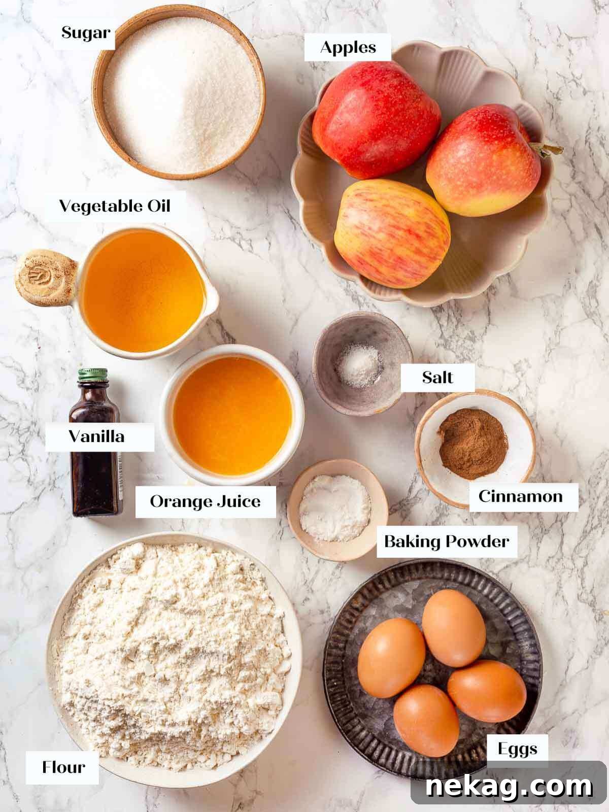 Spiced Apple Harvest Cake 4 All the fresh ingredients for a Jewish apple cake, neatly laid out on a white marble surface, including whole apples, flour, sugar, and citrus.