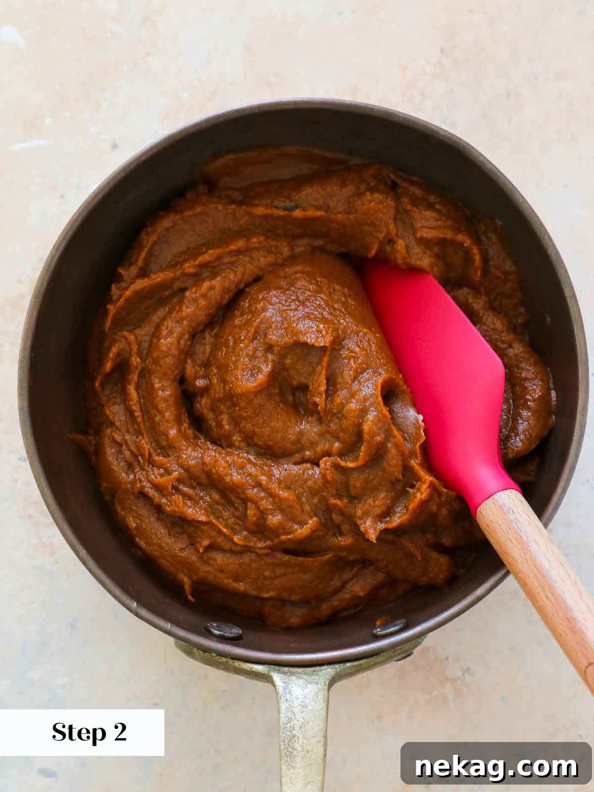 Cooked pumpkin butter simmering and thickening in a beautiful copper pot on the stovetop.