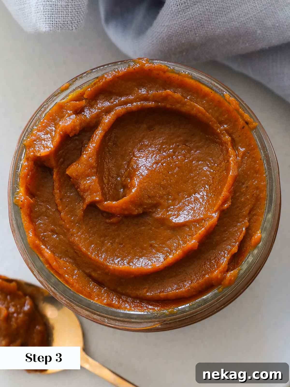 A mason jar filled with freshly made, rich pumpkin butter, showing a beautiful swirl and smooth texture.