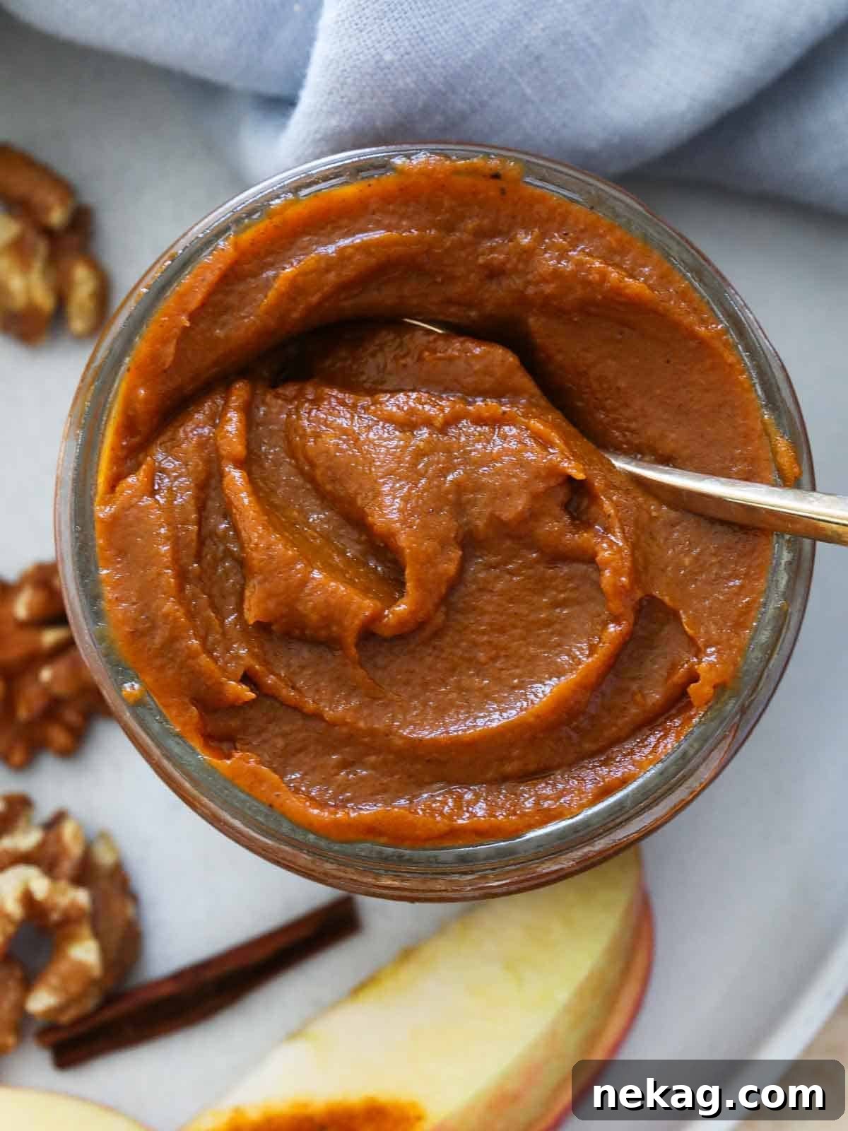 A spoon dipped into a glass jar of homemade pumpkin butter, ready to be enjoyed.