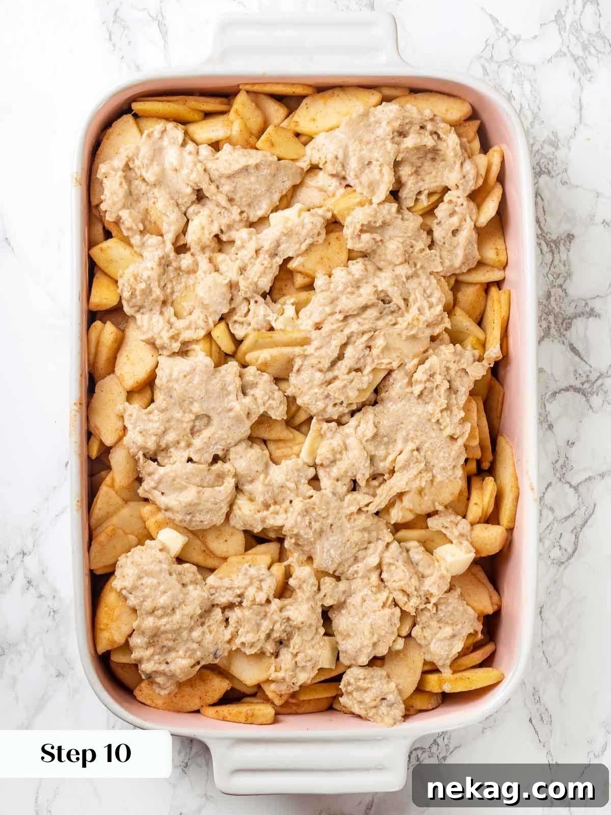 Apple cobbler before baking, showing uncooked ingredients in a dish.