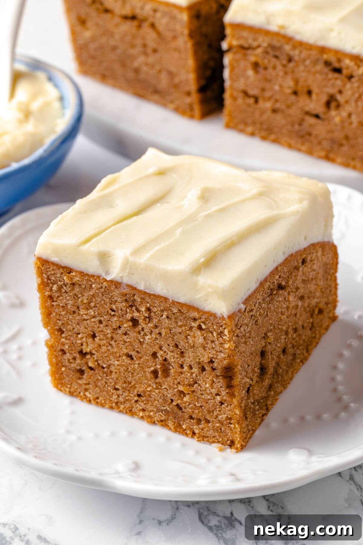 Spiced Applesauce Comfort Cake 4 A perfectly portioned slice of applesauce cake, served on a crisp white plate, highlighting its rich frosting.