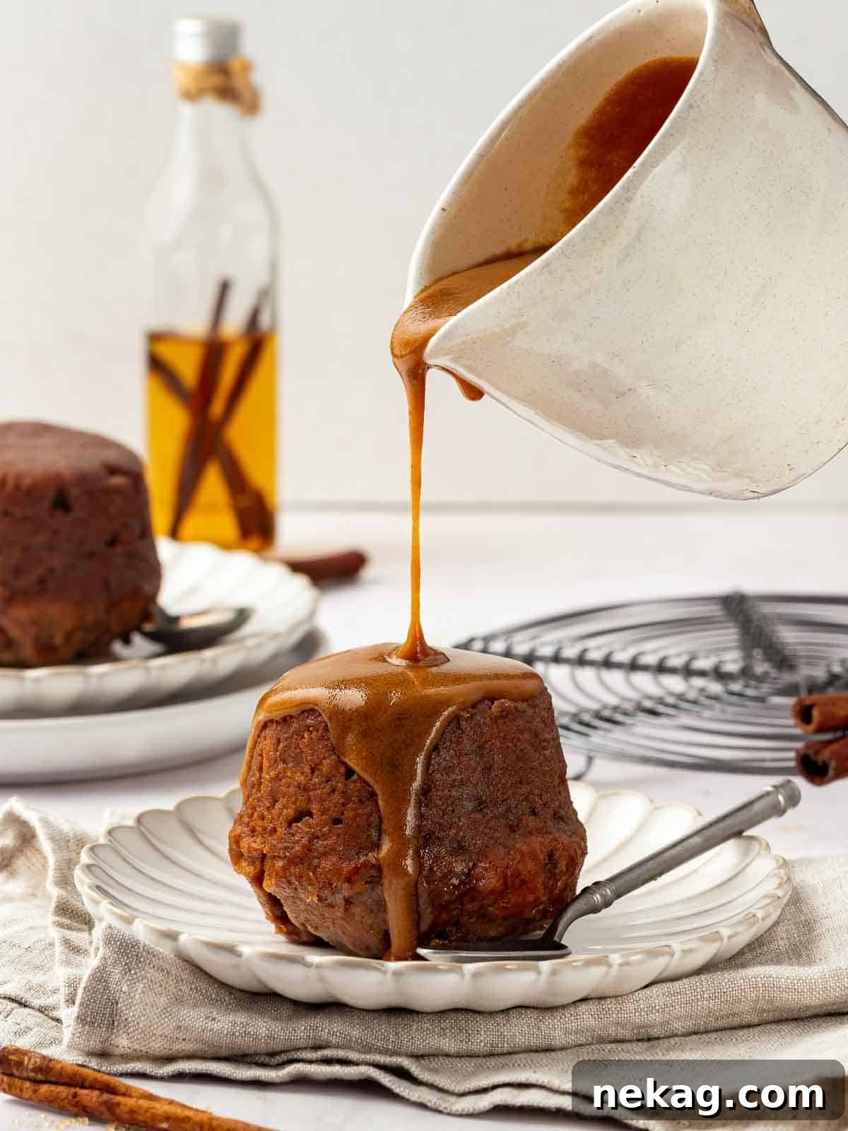 Toffee sauce being poured over sticky toffee pudding, highlighting its rich, moist texture.