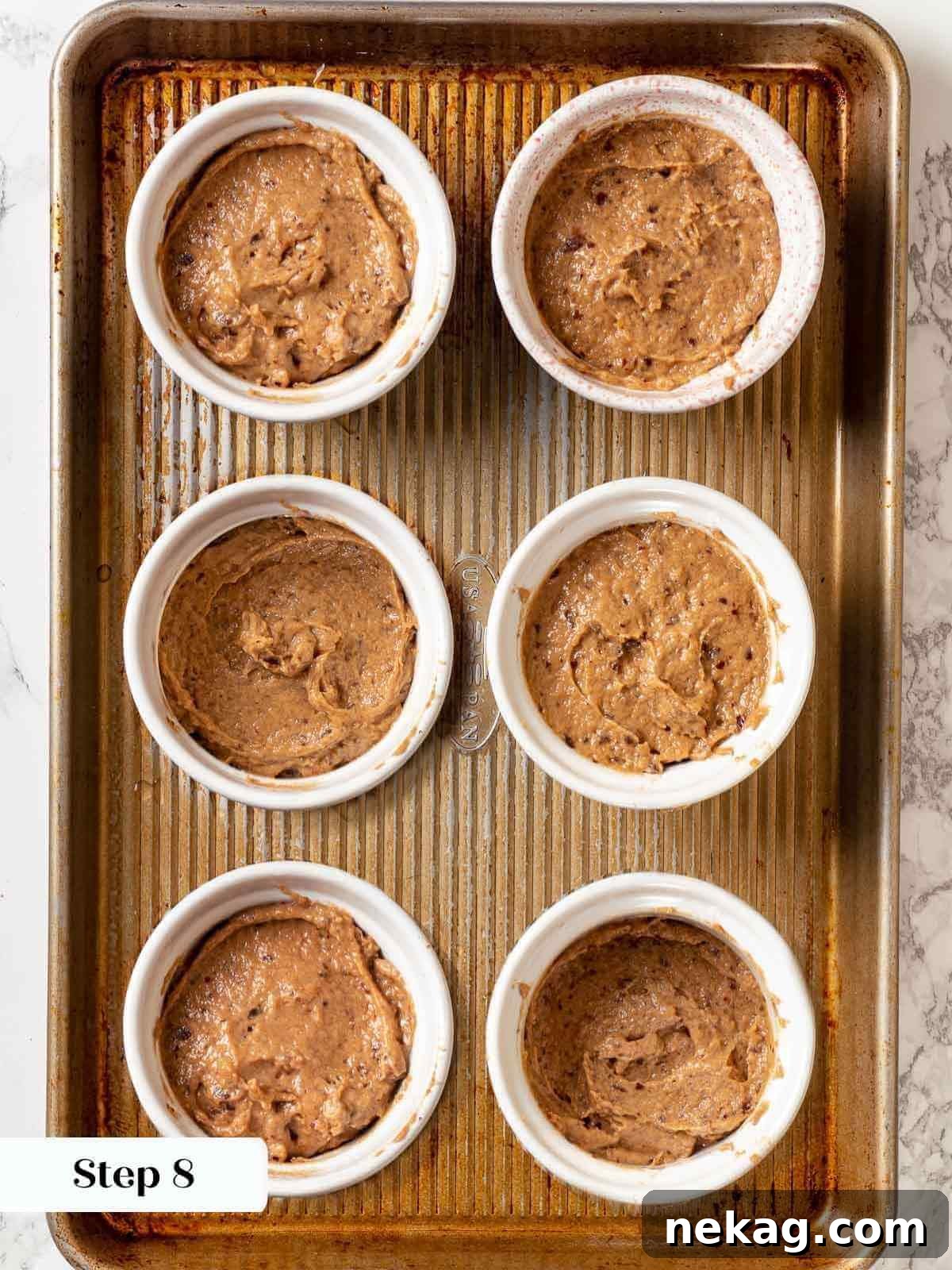 Sticky toffee pudding batter expertly poured into individual ramekins, ready for baking.