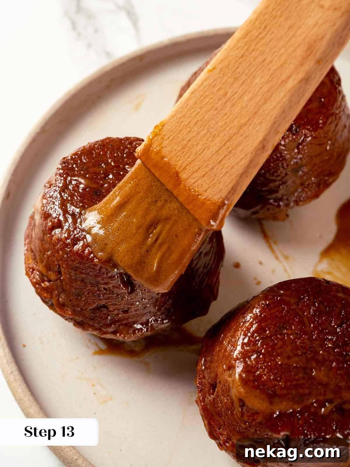 A pastry brush expertly applying glaze on sticky toffee pudding cakes, ensuring even coverage.