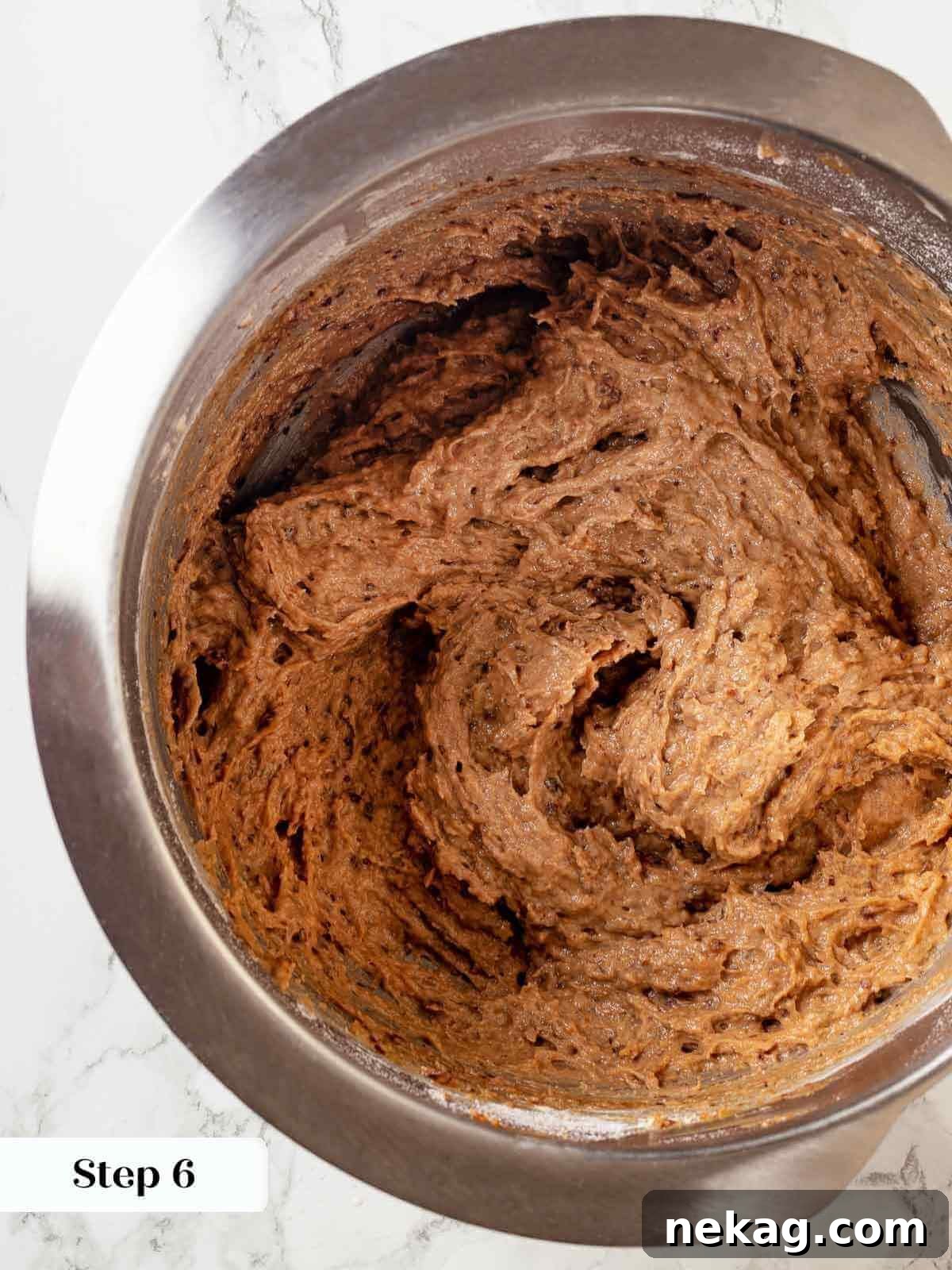 Dry ingredients being gently stirred into the sticky toffee pudding mixture, ensuring a smooth, lump-free batter.