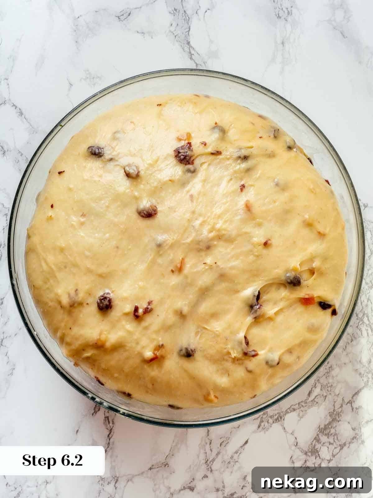 Panettone dough after bulk proofing inside a clear glass bowl, showing its increased volume.
