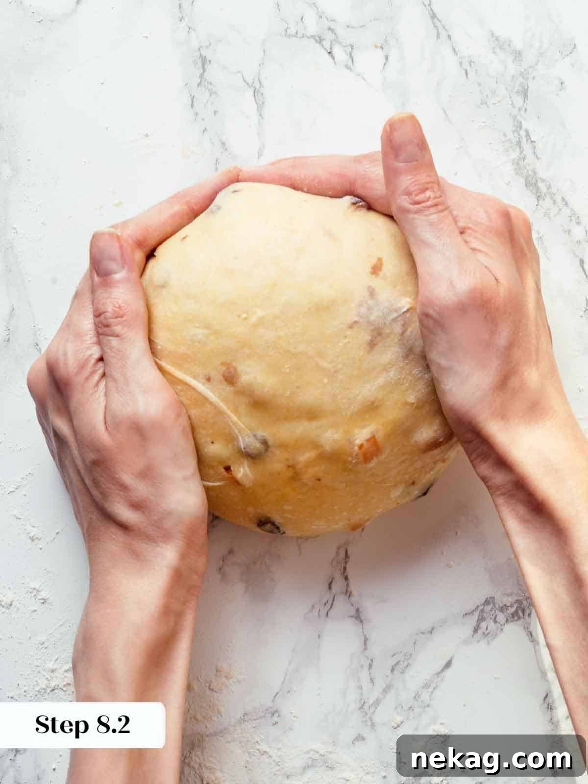 Hands meticulously shaping and tightening panettone dough into a smooth, perfectly round ball.