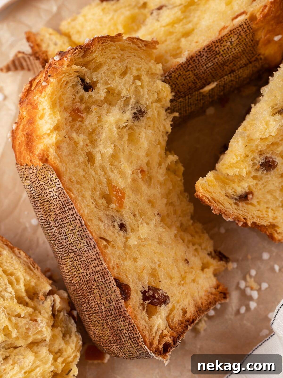 A loaf of baked panettone, beautifully sliced to reveal its rich, buttery interior and even distribution of fruits.
