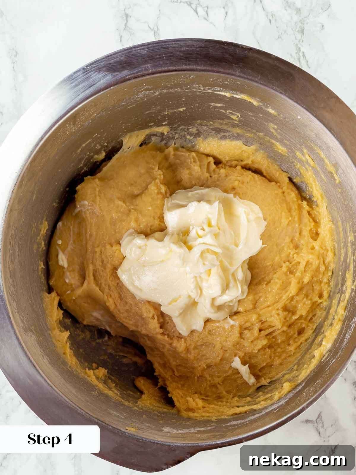 Room temperature butter being incorporated into the panettone dough in a stand mixer.