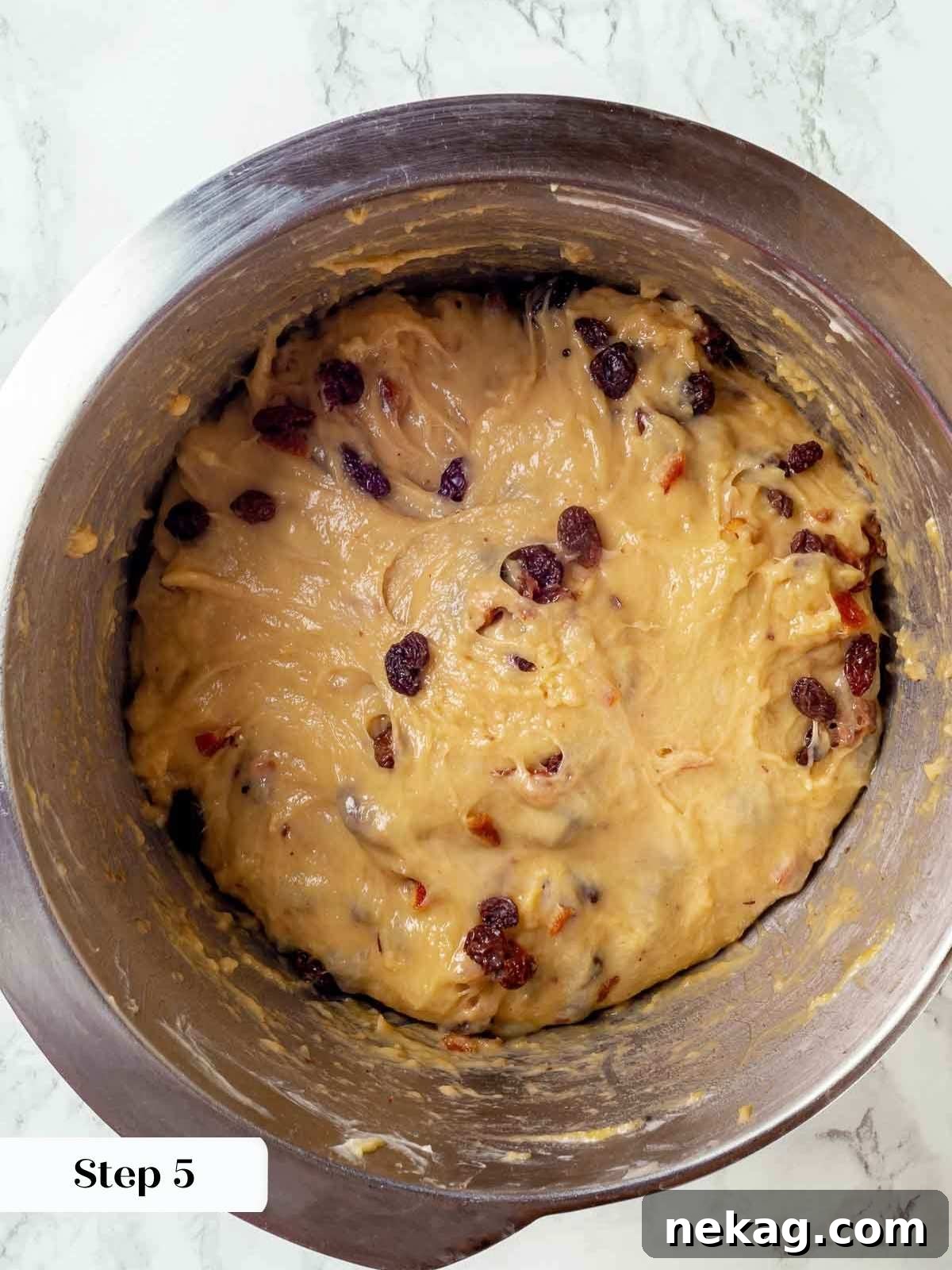 The fruit soaker being added to the panettone dough during the final stages of mixing.