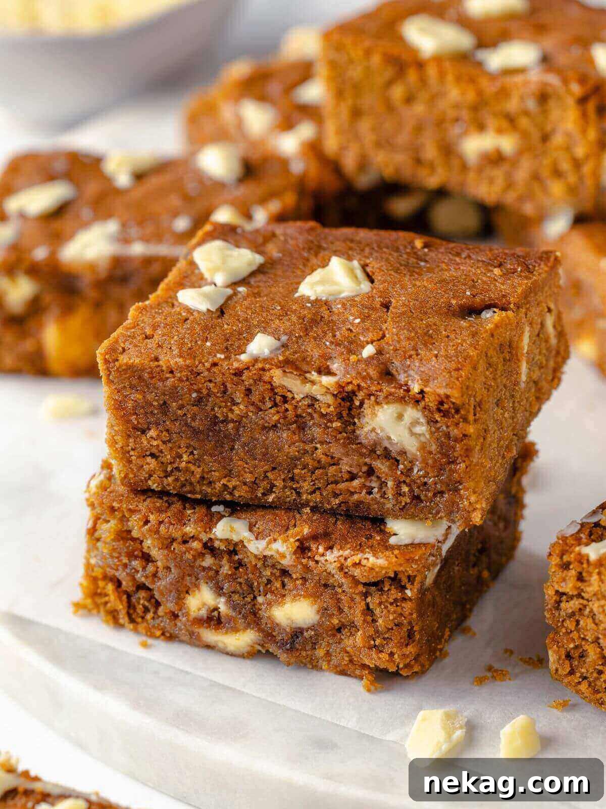 Festive Gingerbread Blondies 13 A captivating close-up of a gingerbread blondie, revealing its tender, spiced interior, generously studded with melted white chocolate pieces, highlighting its irresistible texture.