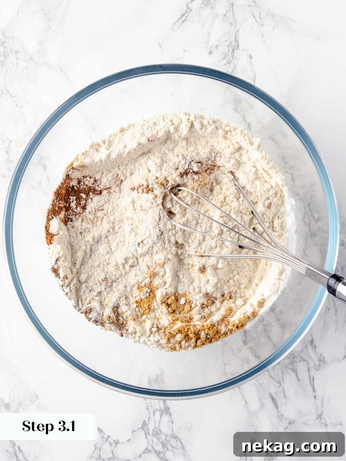 Festive Gingerbread Blondies 5 Dry ingredients for gingerbread blondies being carefully mixed in a large mixing bowl with a whisk, ensuring even distribution of spices and leaveners.