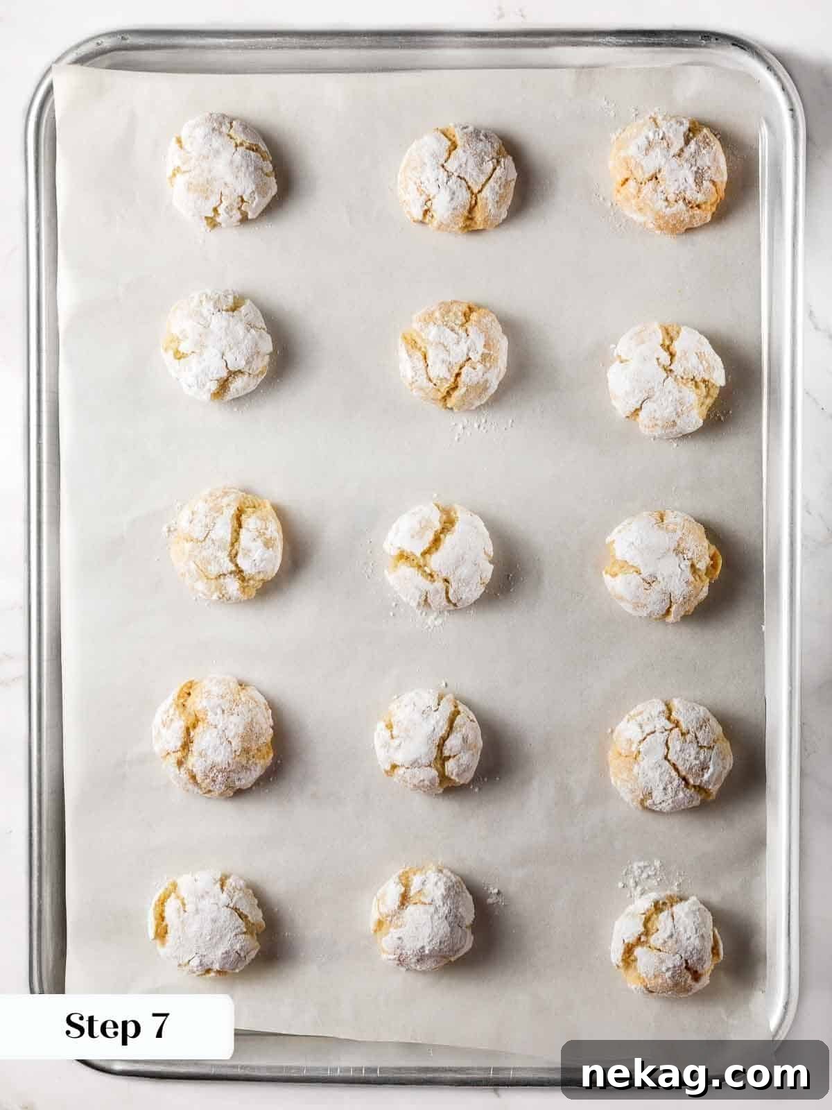 Delicate Amaretti Bites 11 Freshly baked amaretti cookies on a baking sheet, showing their crinkled tops and soft texture.