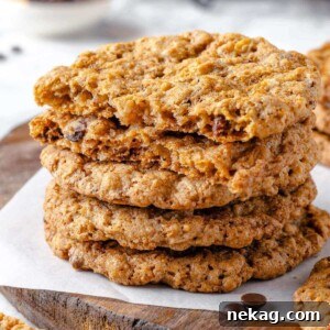 A perfectly baked cowboy cookie broken in half, revealing its dense, chewy interior generously filled with oats, chocolate chips, and pecans, promising a rich and satisfying bite.