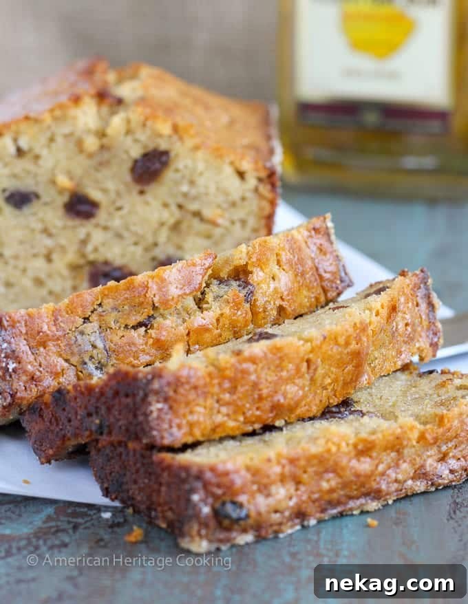 Decadent Brown Butter Rum Raisin Banana Bread 2 Sliced Brown Butter Rum Raisin Banana Bread revealing its moist interior and plump raisins, resting on a rustic wooden board.