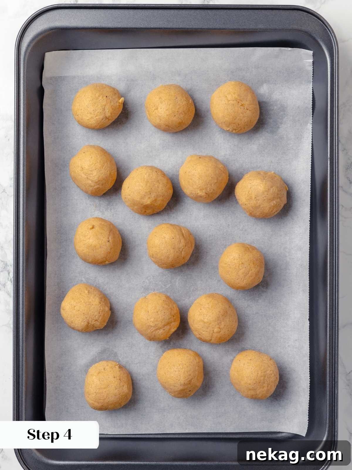 Chilled cookie dough balls on a parchment-lined baking sheet.