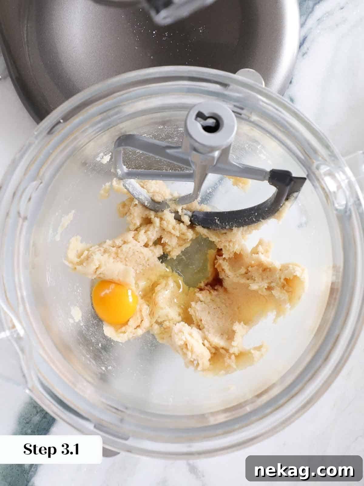 A single raw egg cracked into the mixing bowl, ready to be beaten into the wet ingredients for monster cookie dough.