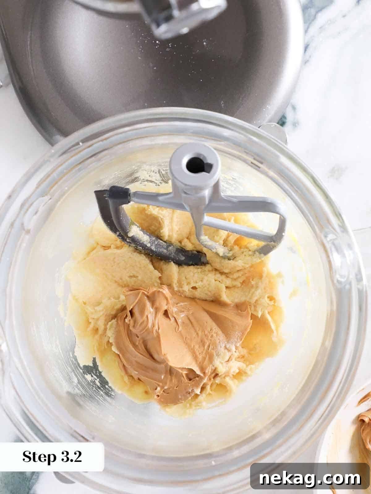 A generous spoonful of creamy peanut butter being added to the wet mixture in a bowl, preparing for the monster cookie dough.
