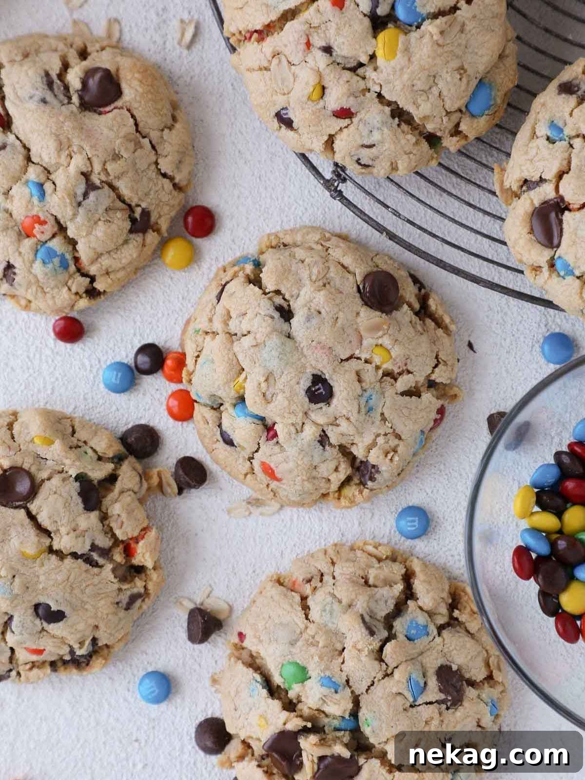 Three perfectly baked monster cookies, showcasing their golden-brown edges and vibrant M&Ms peeking through the surface.