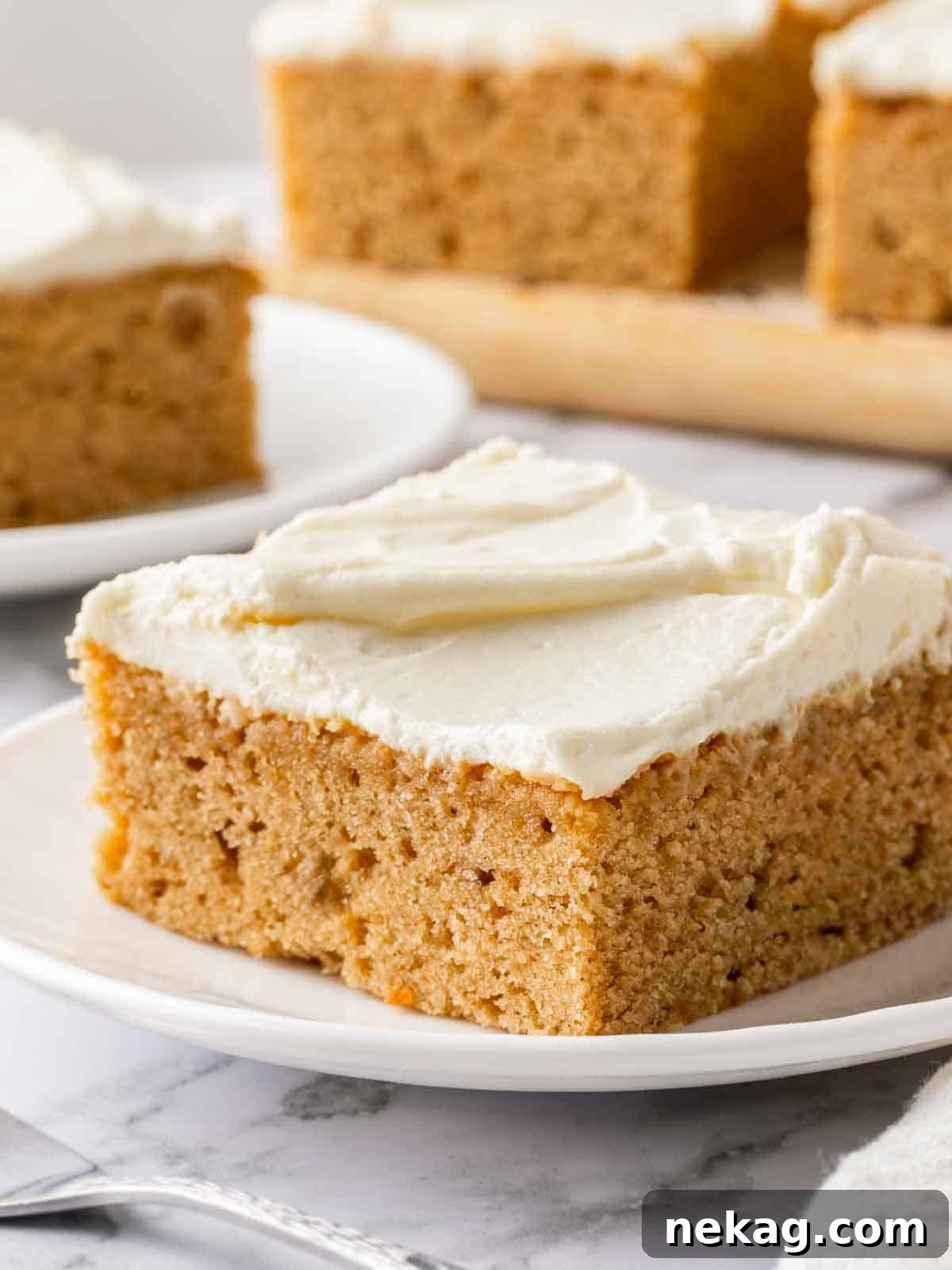 A perfectly sliced piece of moist banana cake, generously topped with fluffy cream cheese frosting, revealing its tender and flavorful interior.