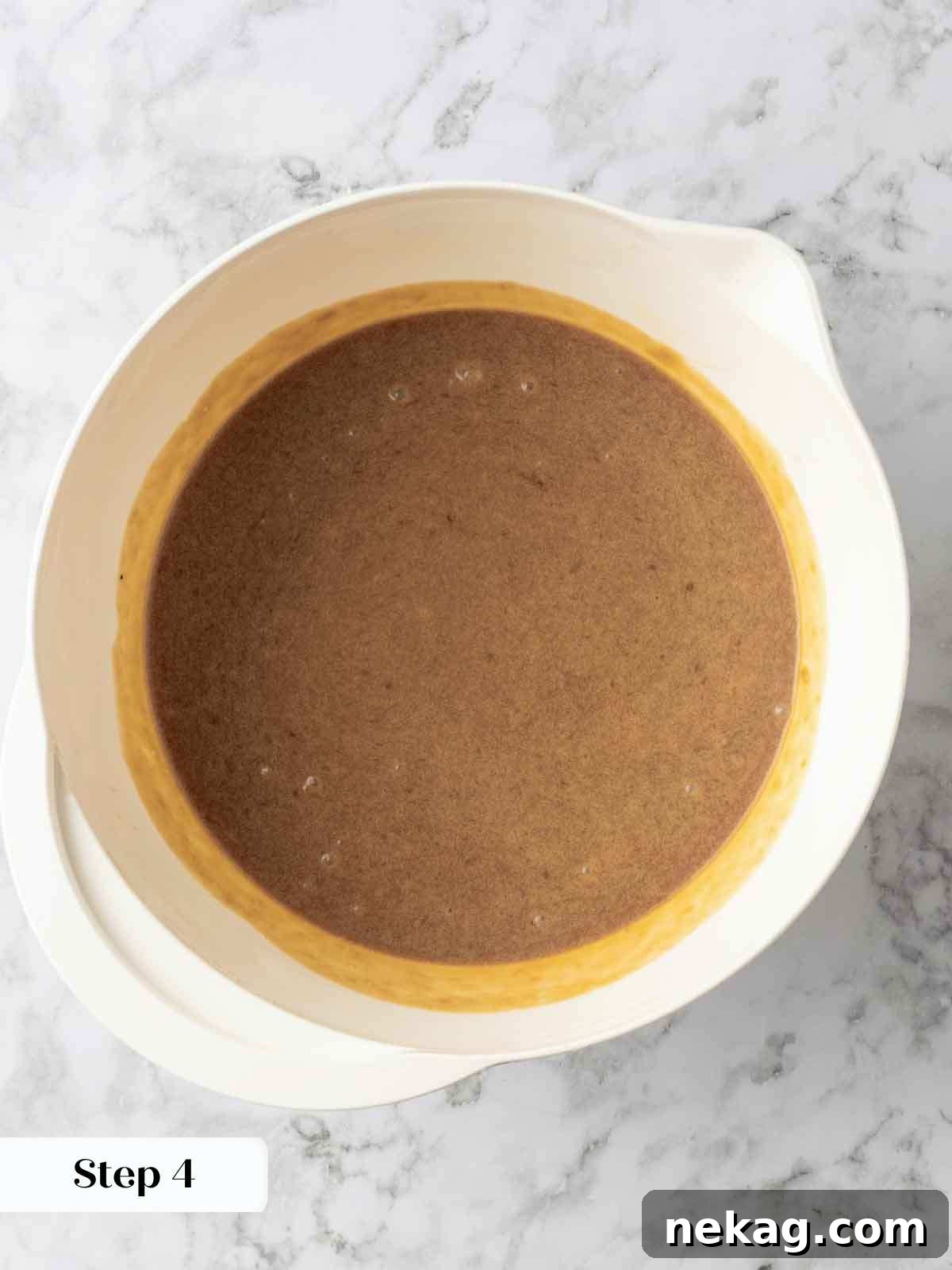A vibrant bowl containing the wet ingredients for banana cake—mashed ripe bananas, eggs, sugars, vanilla, and melted butter—all smoothly combined.