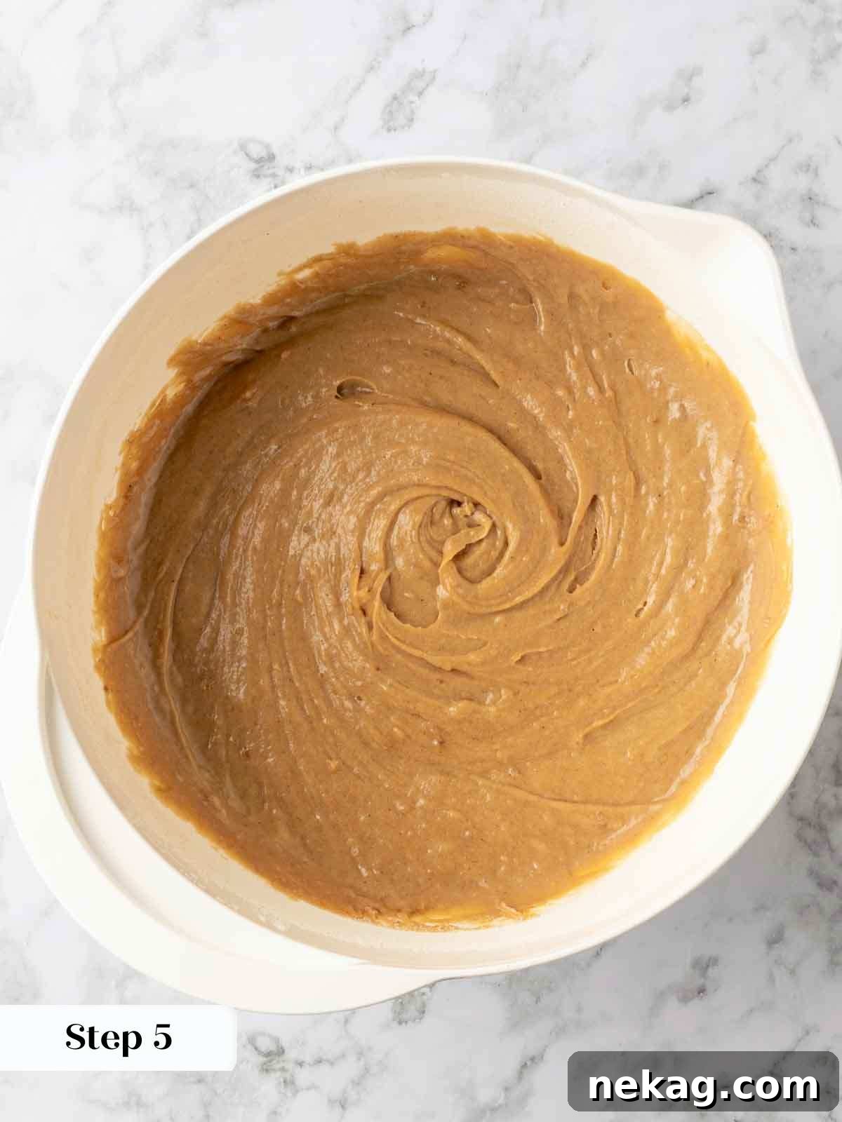 A mixing bowl brimming with rich, creamy banana cake batter, perfectly blended and ready to be transferred to the baking pan.