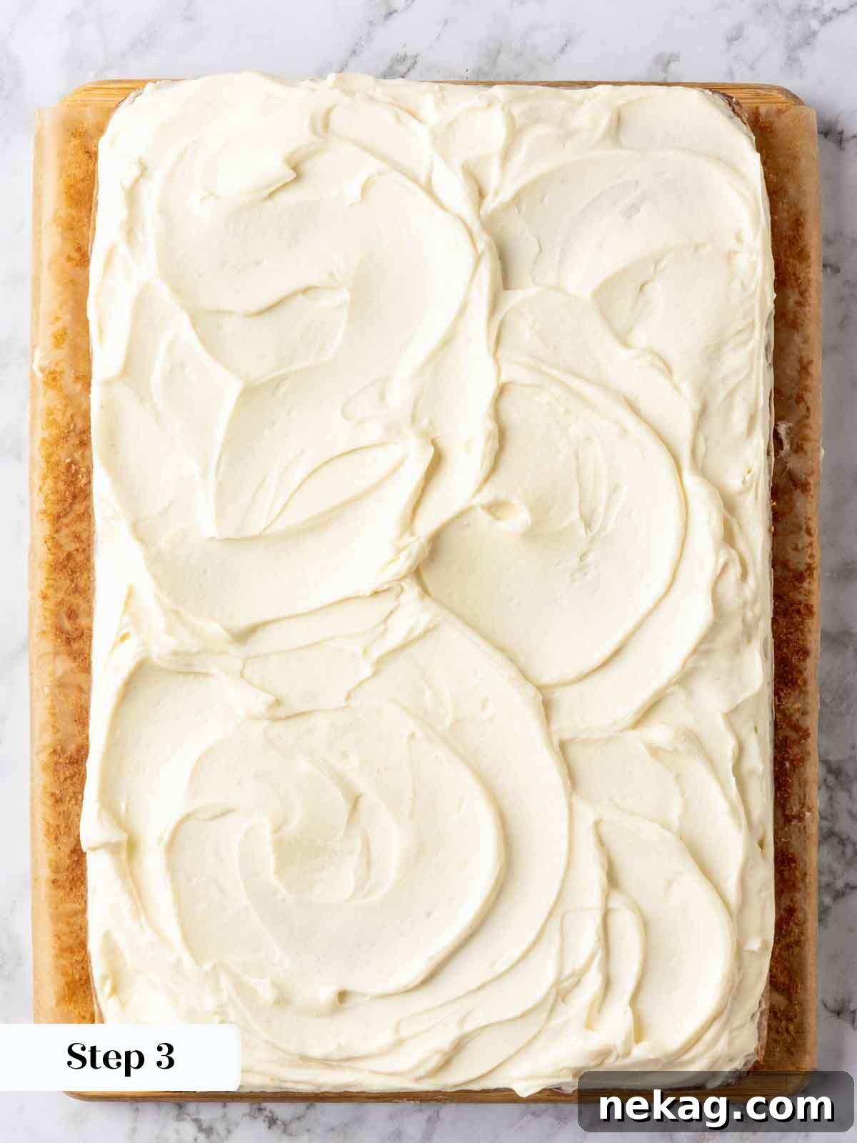 A freshly frosted banana cake, beautifully topped with swirled cream cheese frosting, showcasing its creamy and inviting texture.