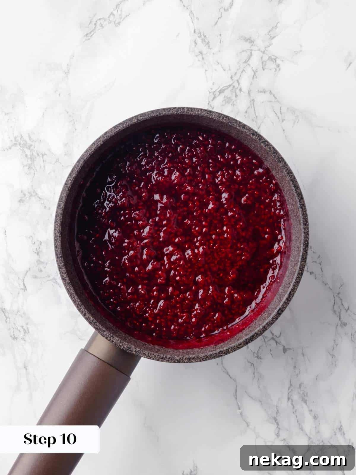 Fresh raspberries cooking in a saucepan to make a smooth and flavorful jam, with steam gently rising.