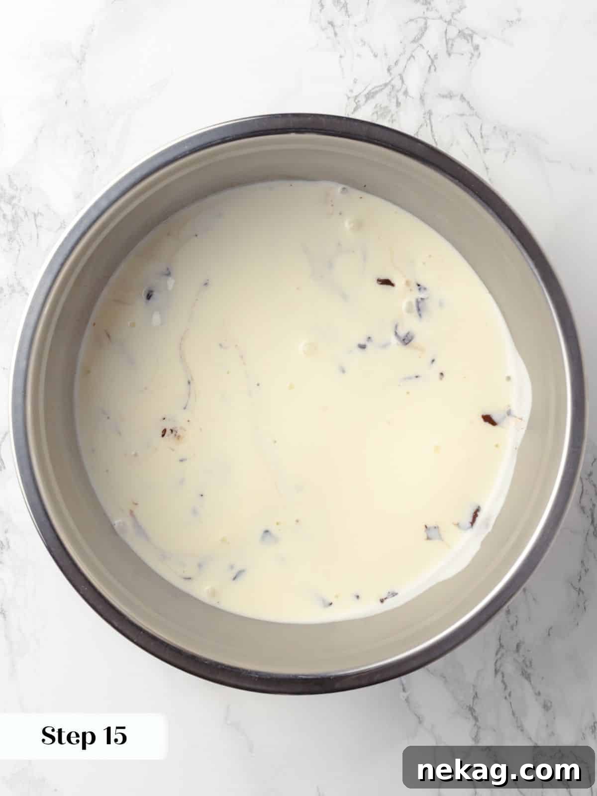 Hot cream being poured over chocolate pieces to create a smooth ganache, showing the melting process.