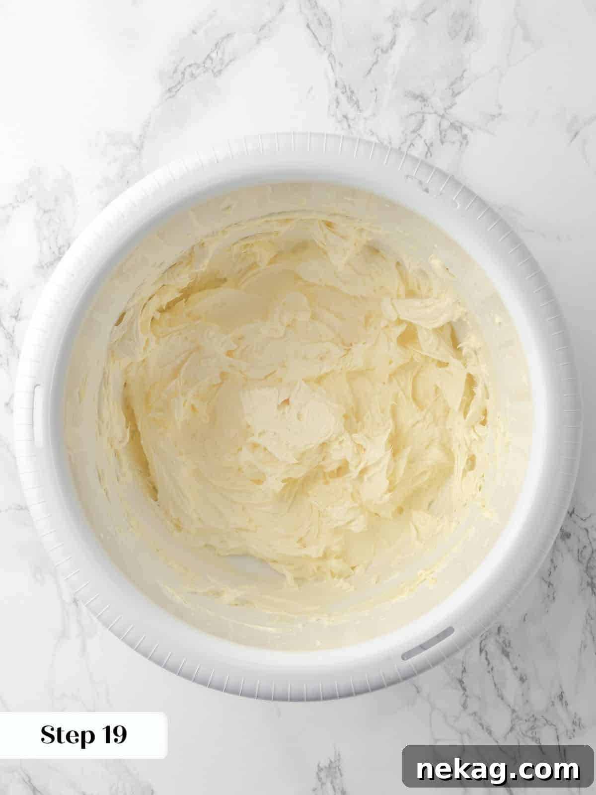 Butter being beaten in a bowl to create a light and fluffy base for buttercream frosting, showing a creamy texture.