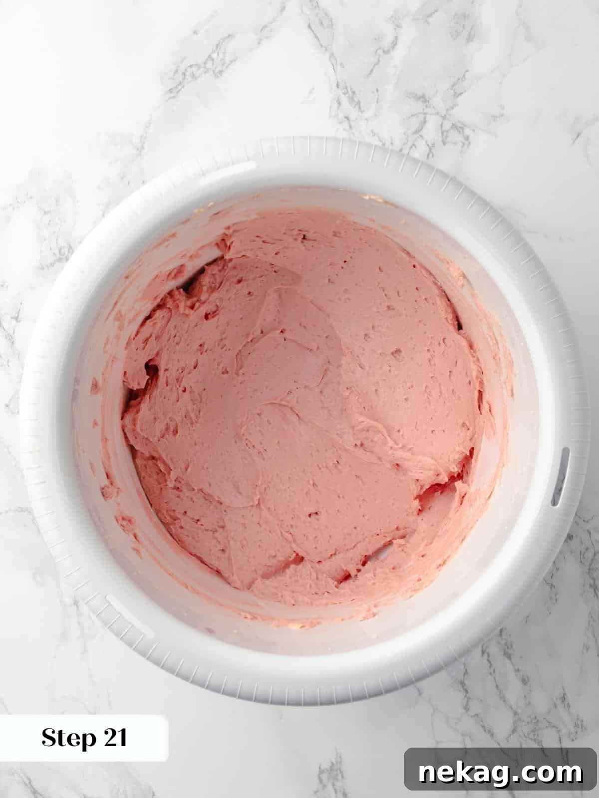 A bowl of pink buttercream frosting swirled and ready to be used for decorating the cake, showcasing its smooth, creamy consistency.